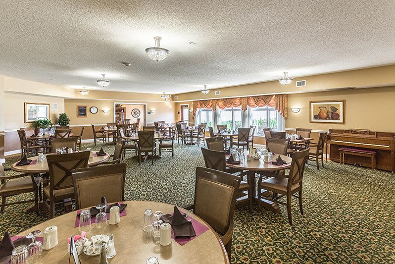 A spacious dining room setup with multiple tables and chairs, featuring elegant decor and large windows.