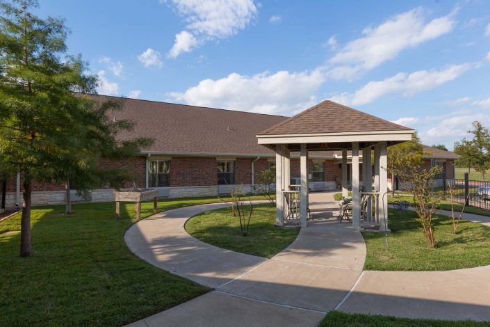 A scenic view of a building with a gazebo and winding pathway under a blue sky.