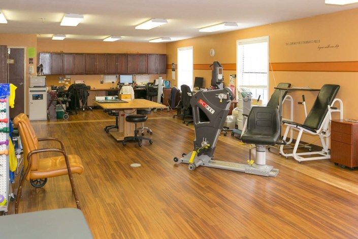 A spacious gym with various exercise equipment and a wooden floor.