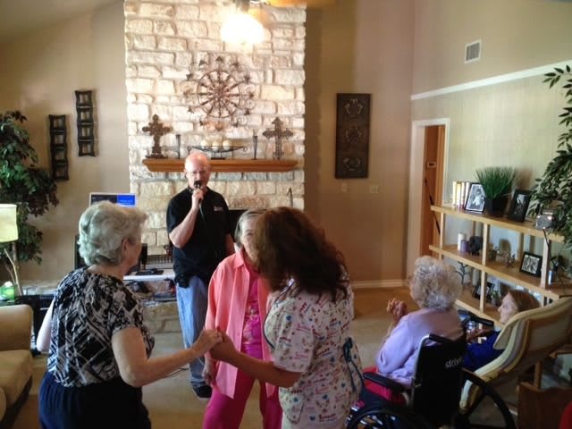 A group of seniors enjoying a dance in a cozy living room setting.
