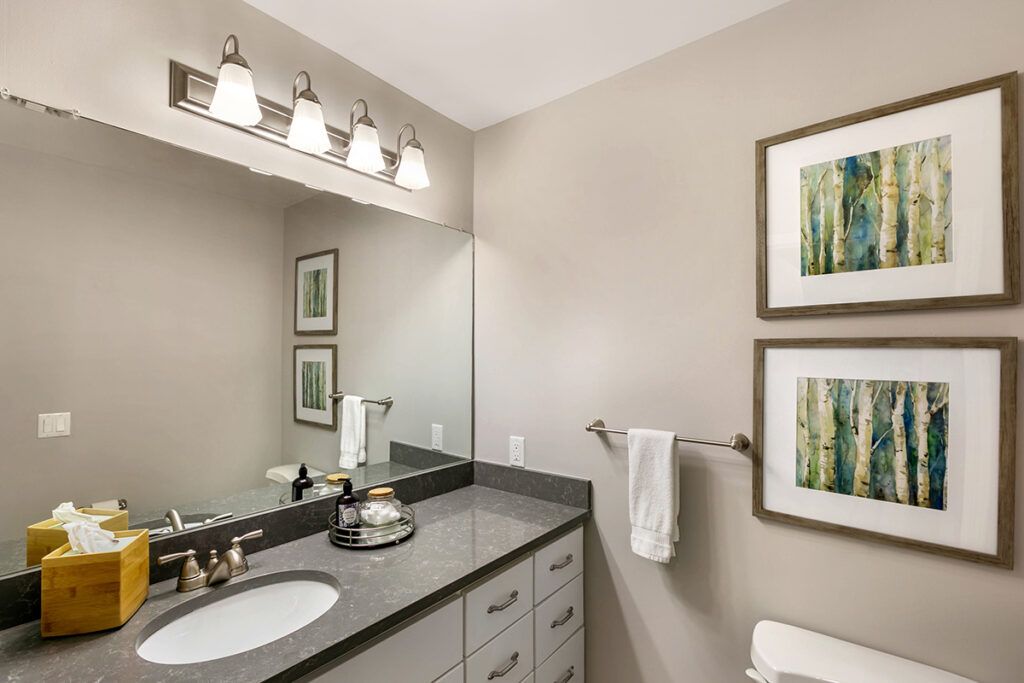 A modern bathroom with a large mirror, elegant lighting, and minimalist decor.