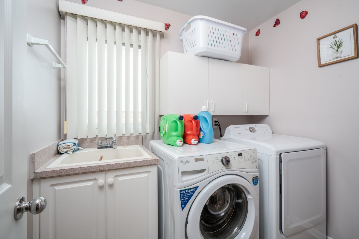 A tidy laundry room featuring a washing machine, dryer, and cleaning supplies.
