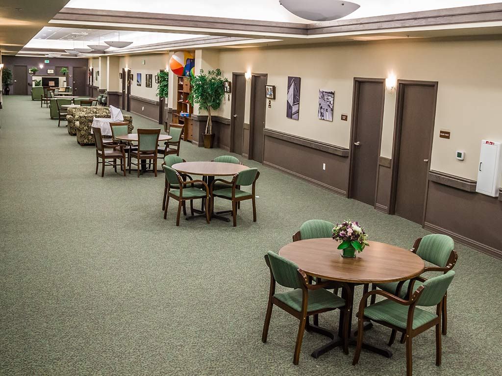 A spacious dining area with neatly arranged tables and chairs, decorated with plants and wall art.
