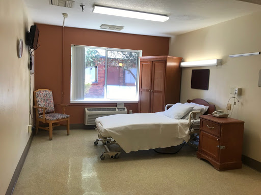 A bright and clean hospital room featuring a patient bed, window, and essential furniture.