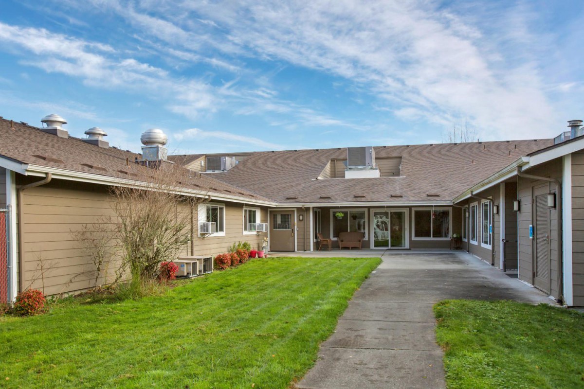 A residential house with a well-maintained lawn under a cloudy sky.