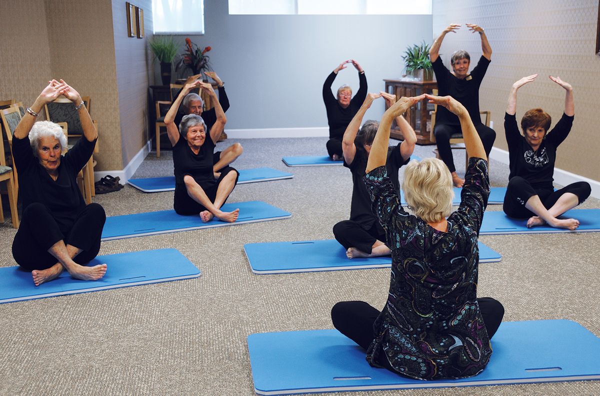 A group of senior citizens practicing yoga together indoors.