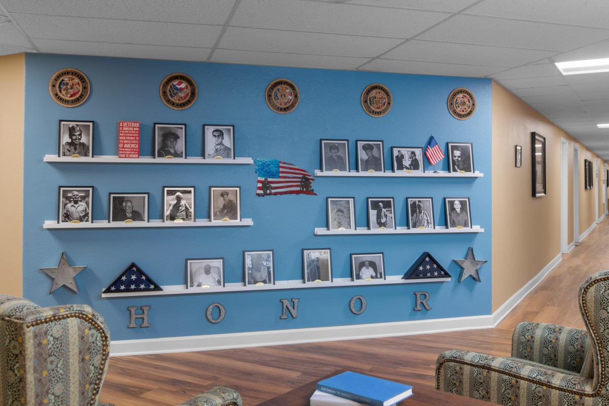A memorial wall displaying photographs and flags to honor military service members.