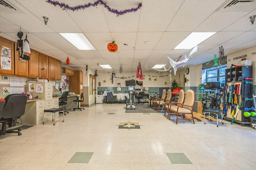 A spacious community room decorated with Halloween themed items, featuring exercise equipment and seating arrangements.