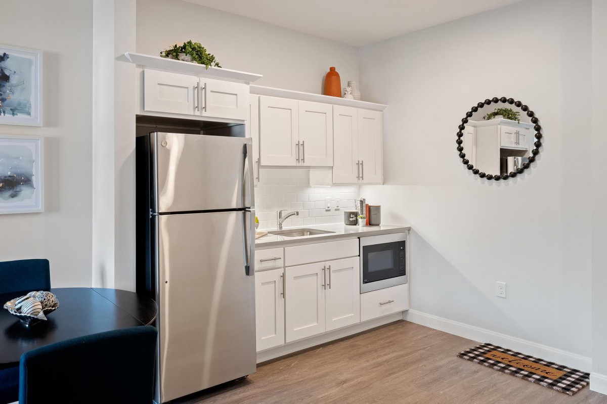 A modern kitchen with white cabinets, a stainless steel refrigerator, and a microwave.