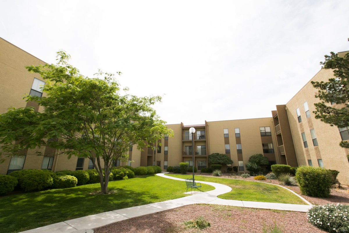 An outdoor view of an apartment building with landscaped gardens and pathways.