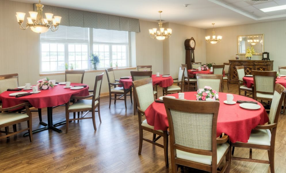 A cozy dining room with elegantly set tables covered in red tablecloths.