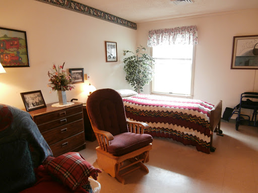 A cozy and simple bedroom featuring a bed, rocking chair, and decorative elements.