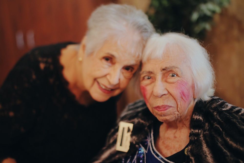 Two elderly women smiling together in a warm and affectionate portrait.