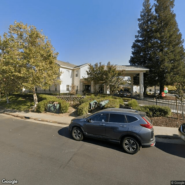 A street view of a building with trees and a parked car during the day.