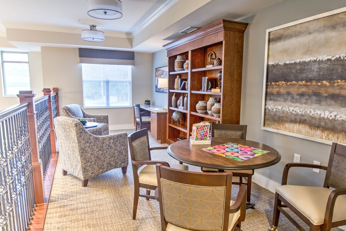A cozy living room featuring a bookshelf, seating area, and game table.