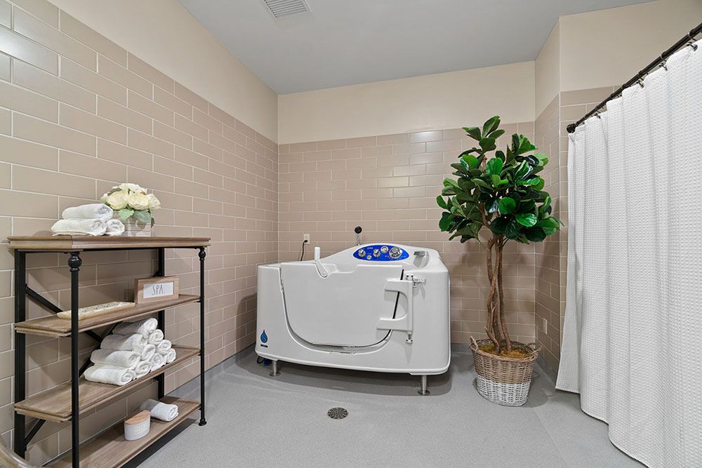 A bathroom with a modern bathtub, neatly stacked towels on shelves, and a decorative plant.