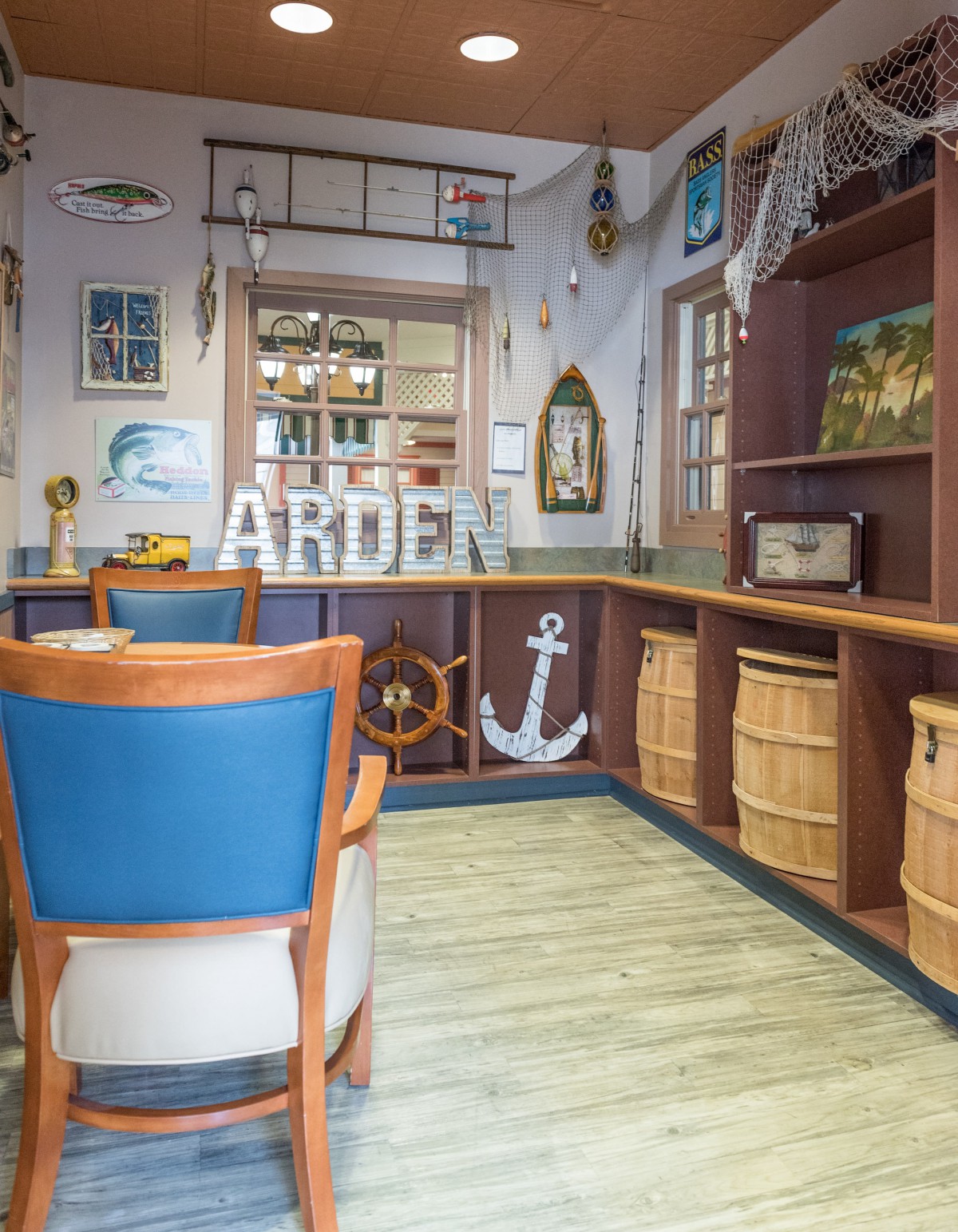 A nautical-themed room with blue chairs, wooden elements, and decorative anchors.
