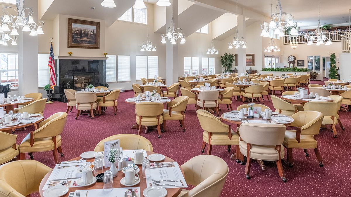 A spacious dining room with neatly arranged tables and chairs, featuring bright lighting and a cozy atmosphere.