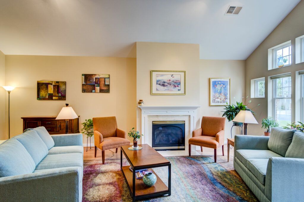 A cozy and modern living room features a central fireplace, comfortable seating, and tasteful artwork.