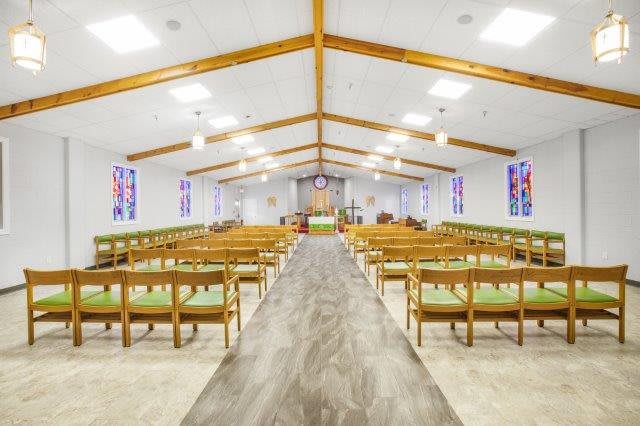 Interior view of a church with wooden pews and stained glass windows.