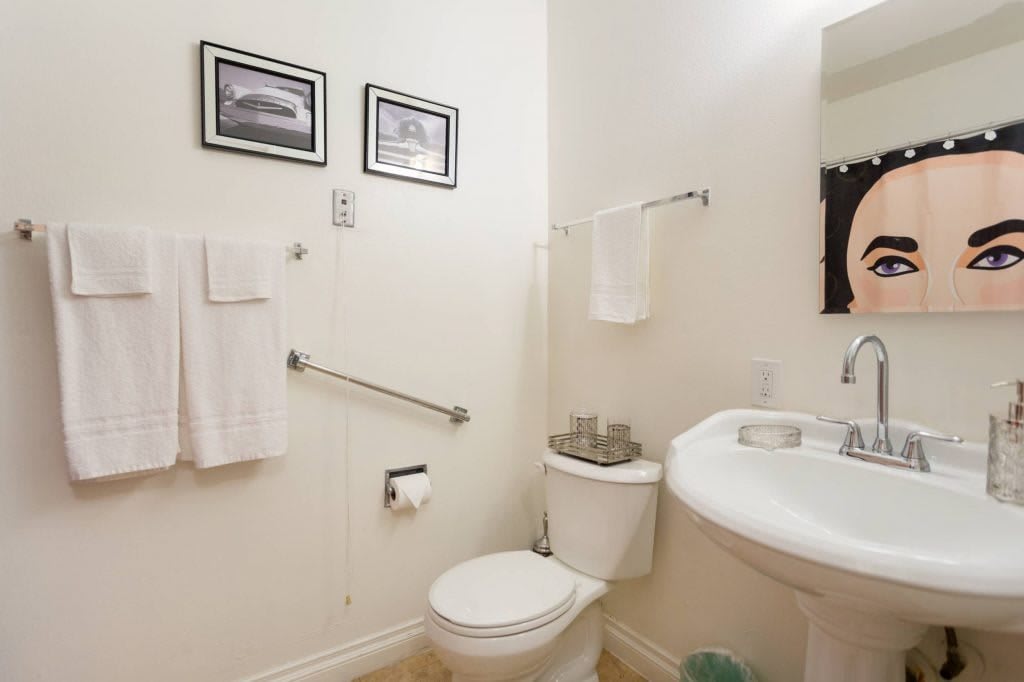 A clean and tidy bathroom featuring a toilet, sink, towels, and wall art.