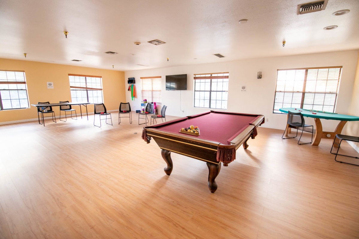 A spacious recreation room featuring a pool table and various seating areas.