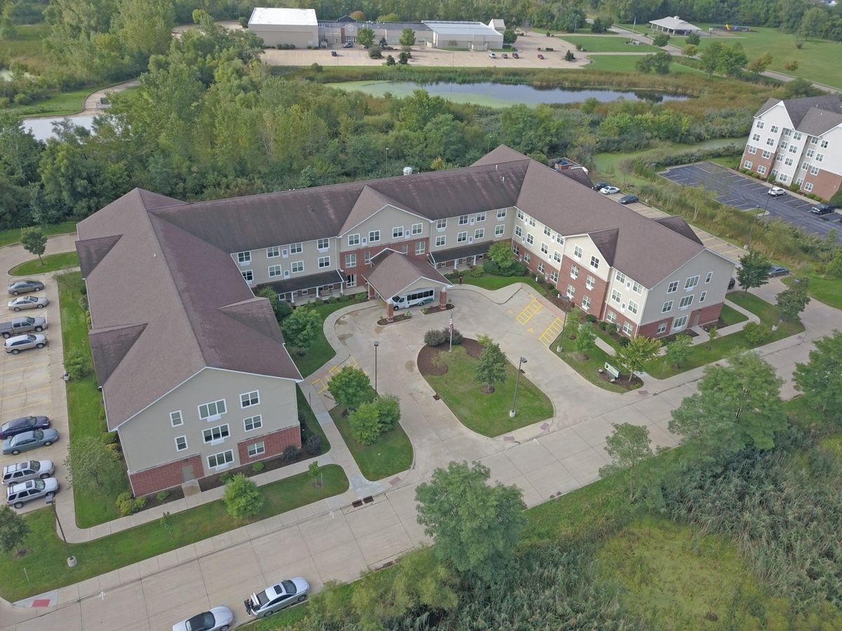 Aerial view of a large building surrounded by trees and a parking lot.