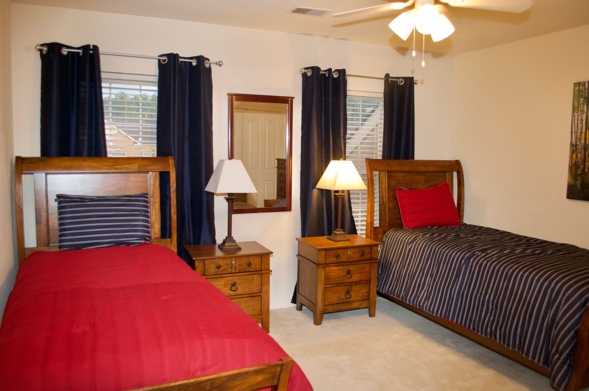 A cozy bedroom with twin beds featuring red bedding, flanked by wooden nightstands and lamps.