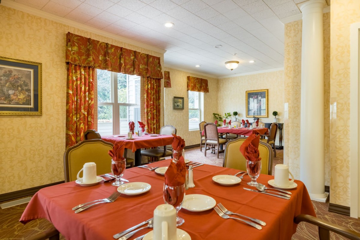 An elegantly set dining room with red tablecloths and neatly arranged tableware.