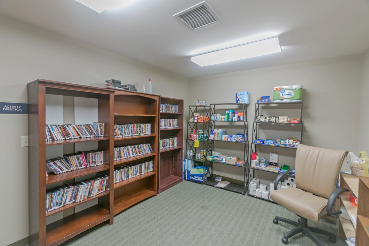 A small room with organized shelves filled with books and DVDs.