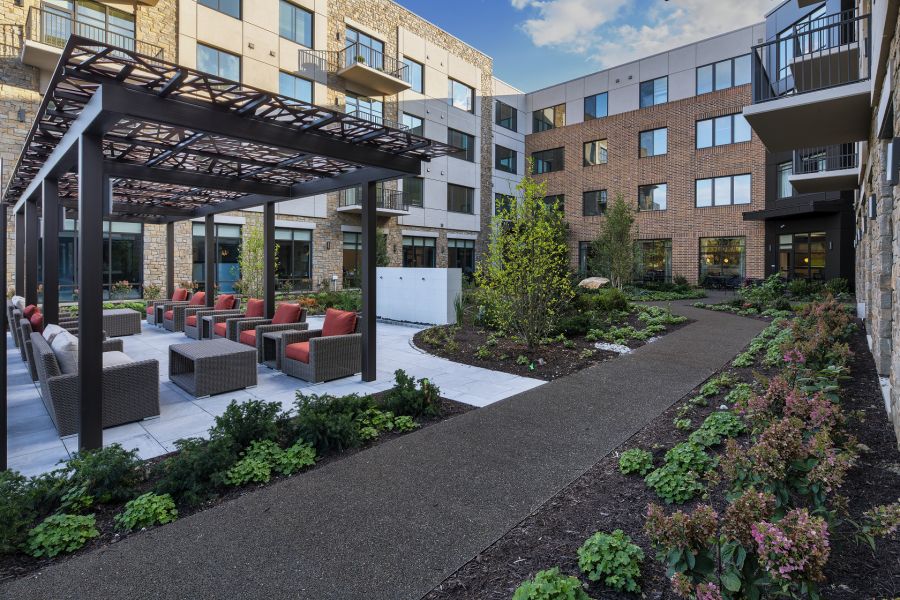 A modern apartment complex features a well-maintained outdoor seating area and landscaped gardens.