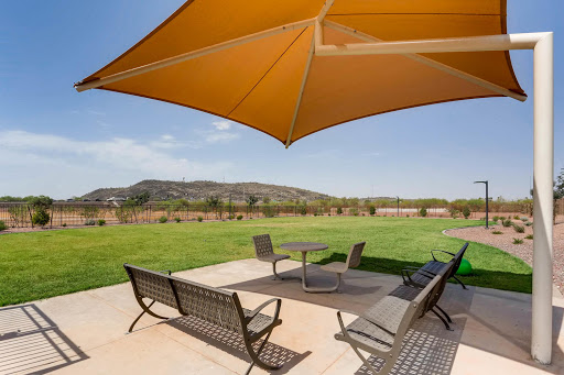 A cozy outdoor patio area featuring comfortable furniture and a large umbrella, set against a scenic backdrop of rolling hills.