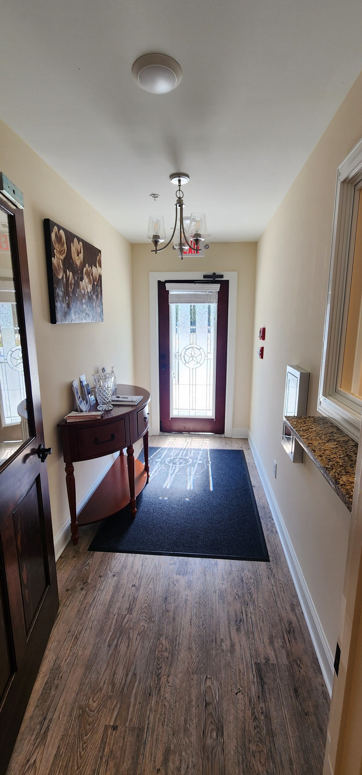 A cozy hallway with a small table, a painting on the wall, and a door leading outside.