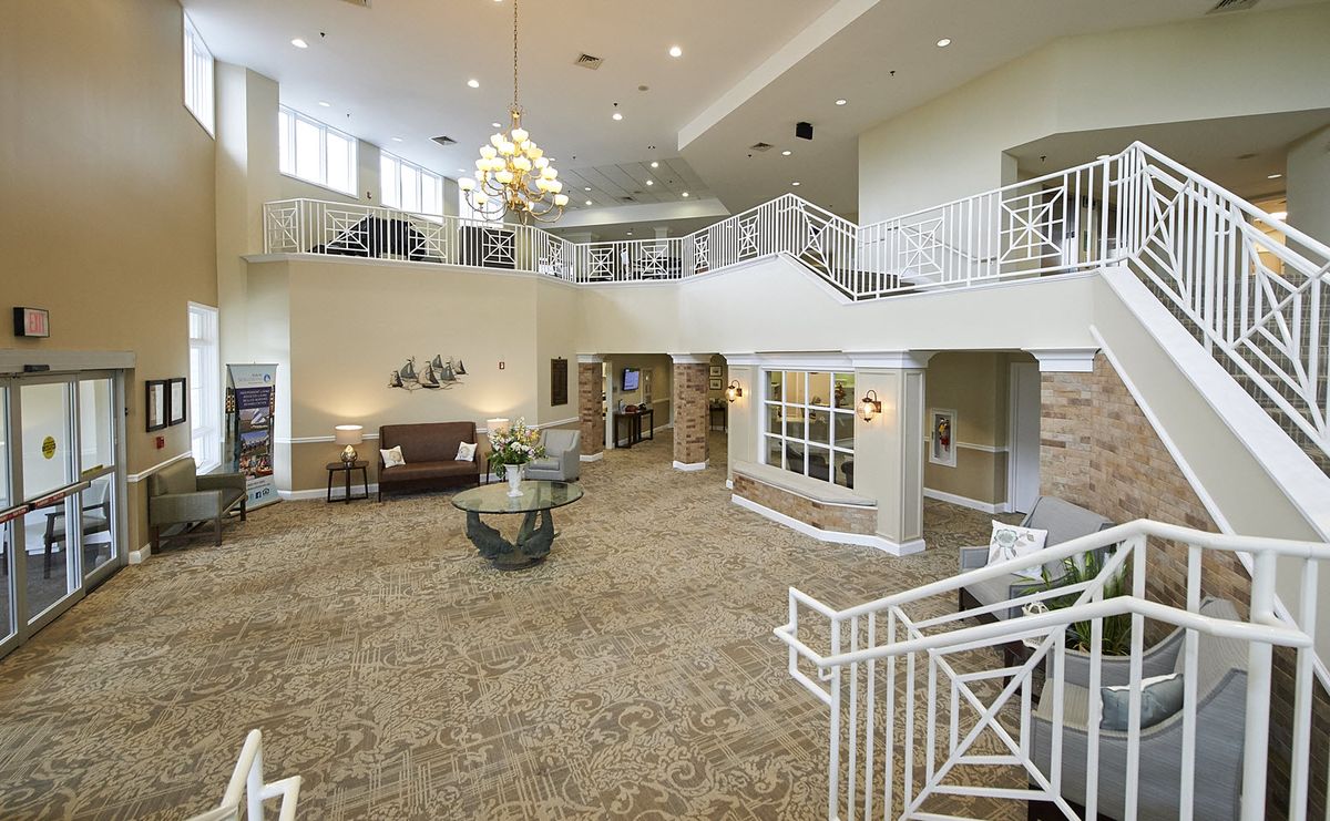 A spacious and elegantly designed lobby with a chandelier, featuring carpeted flooring and stylish railings.