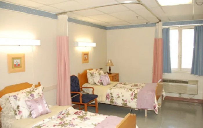 A hospital room with neatly arranged beds and privacy curtains.