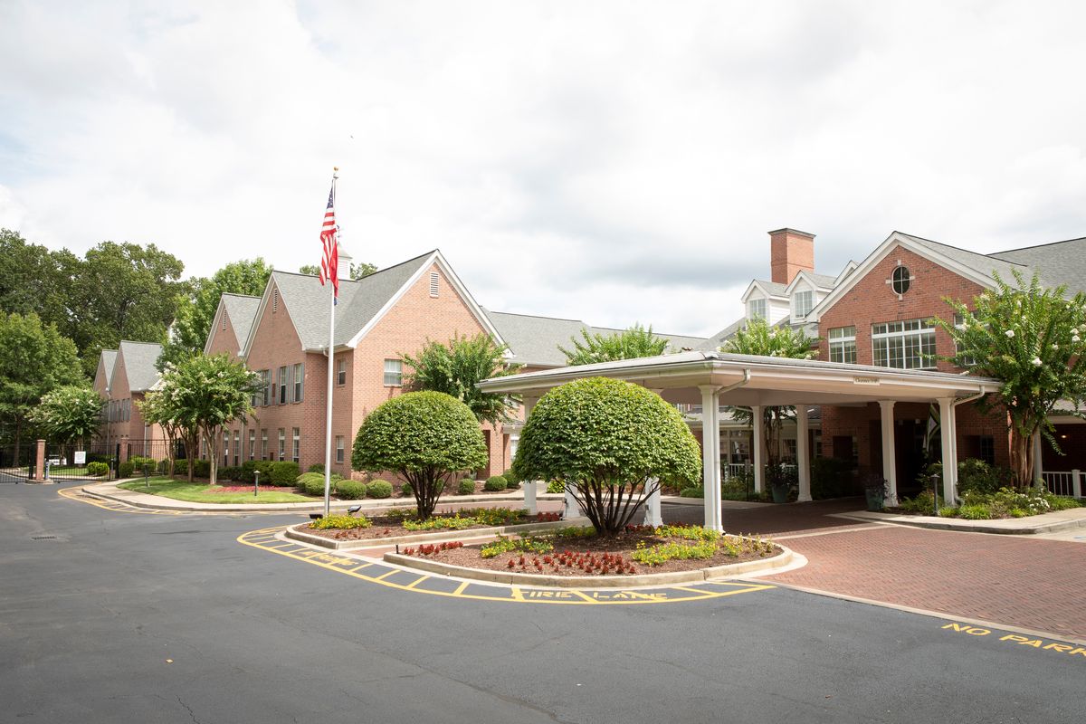 A brick building with a landscaped driveway and an American flag at the entrance.