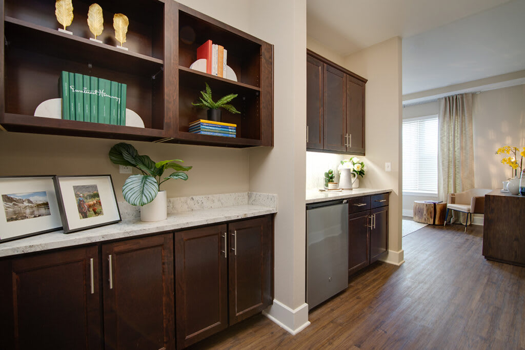 A modern kitchen interior with dark wood cabinets and open shelves, featuring sleek appliances and a light countertop.