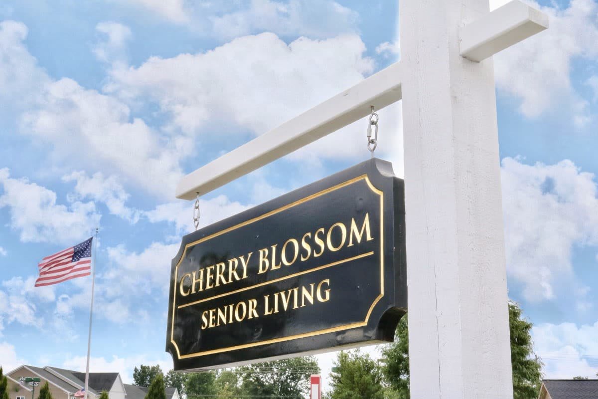 A sign for Cherry Blossom Senior Living against a backdrop of blue sky and clouds.