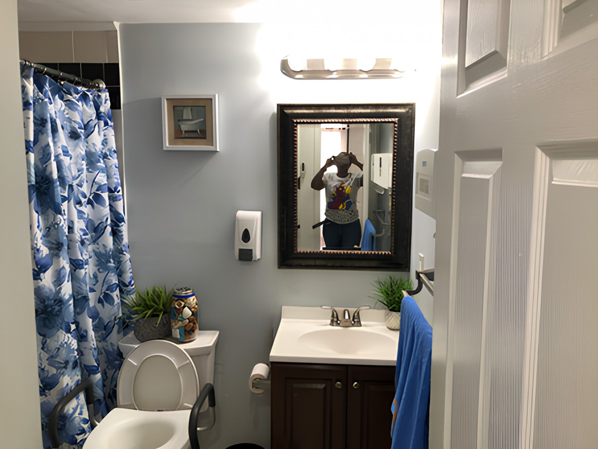 A clean and organized bathroom with a blue shower curtain, mirror, and modern fixtures.