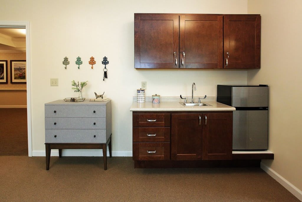 Modern kitchenette with wooden cabinets and a small refrigerator.