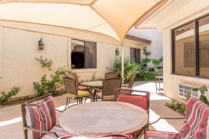 A sunny patio with comfortable seating and shade.
