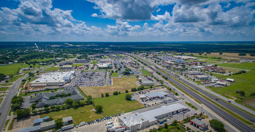 A panoramic aerial view of an industrial zone with low-rise buildings and a highway under a partly cloudy sky.