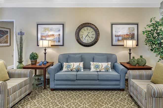 A cozy living room featuring a blue sofa, decorative pillows, and matching side tables with lamps.