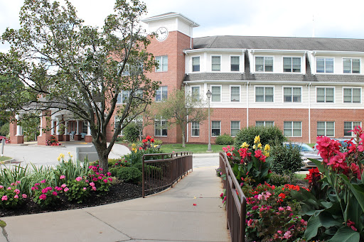 A scenic view of a residential building surrounded by vibrant flowers and greenery.