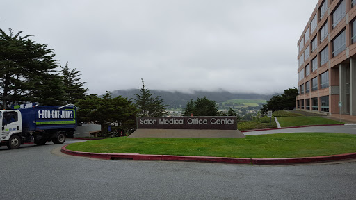 A view of the Sign Medical Office Center against a backdrop of cloudy hills.