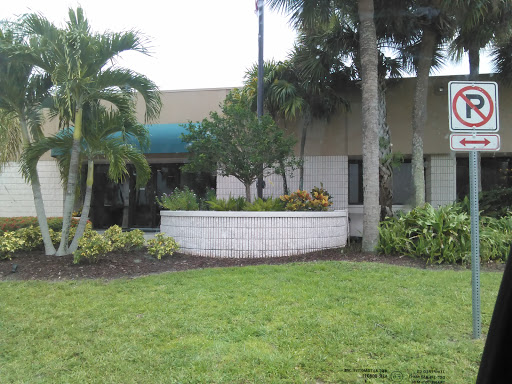 A well-maintained building entrance surrounded by lush greenery and palm trees.