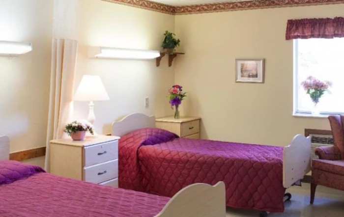 A cozy bedroom with twin beds adorned in purple bedding, complete with nightstands and decorative plants.