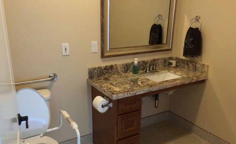 A bathroom with a granite countertop, sink, and mirror.