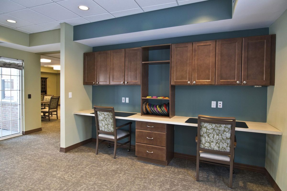 A modern office workspace with built-in desks, cabinets, and chairs.