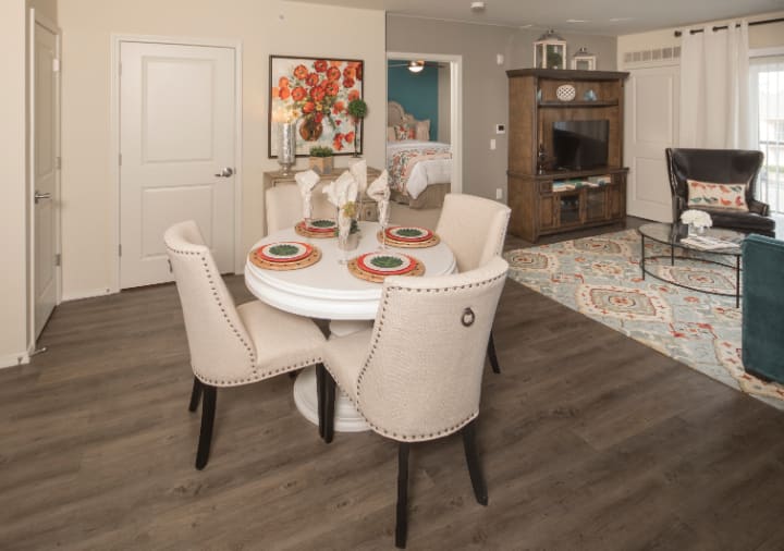 A stylish dining area with a round table set for four, featuring elegant chairs and decorative elements in a cozy living space.
